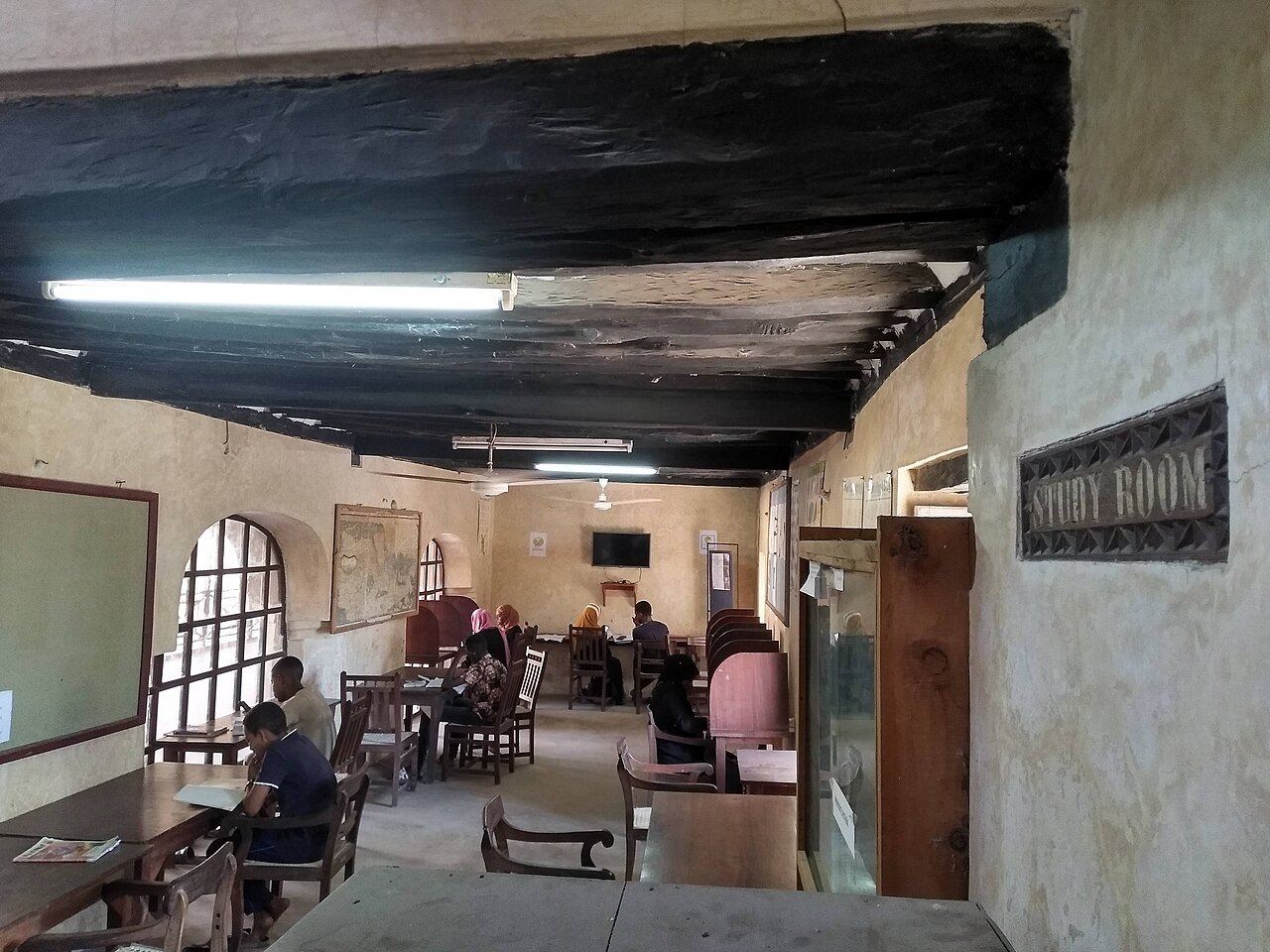 Sala di studio della biblioteca del forte di Lamu in Kenya, con persone sedute ai tavoli; fotografia d’archivio